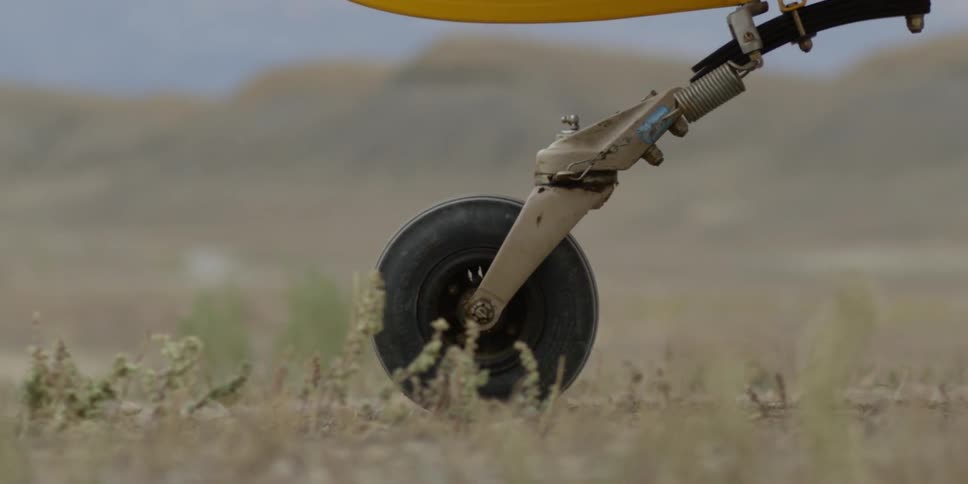 The wheel of the landing gear of a small yellow plane