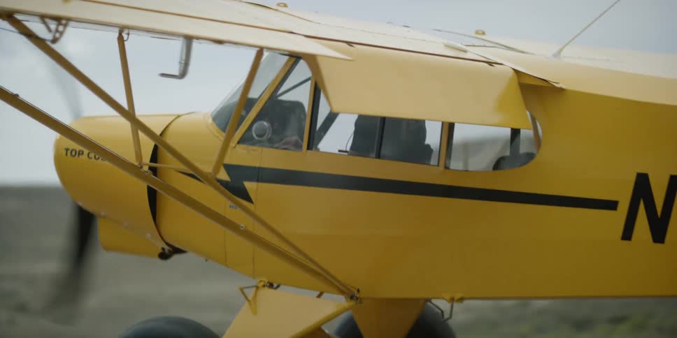 A small yellow single engine plane on an overcast day