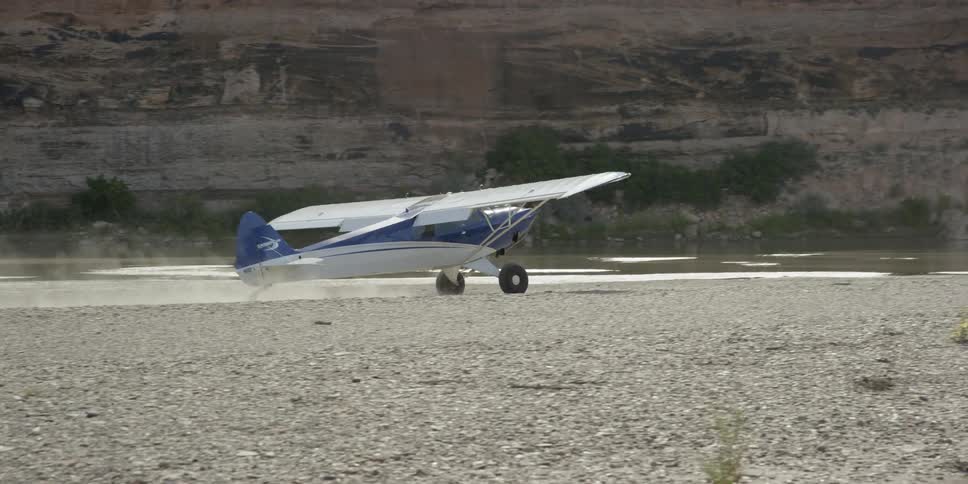 A blue and white airplane takes off in the desert
