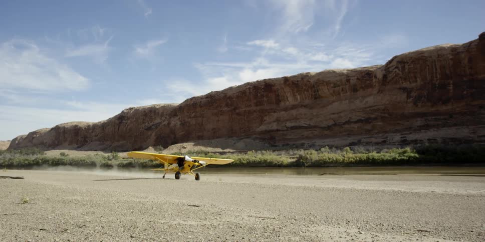 Small yellow plane landing on the dirt