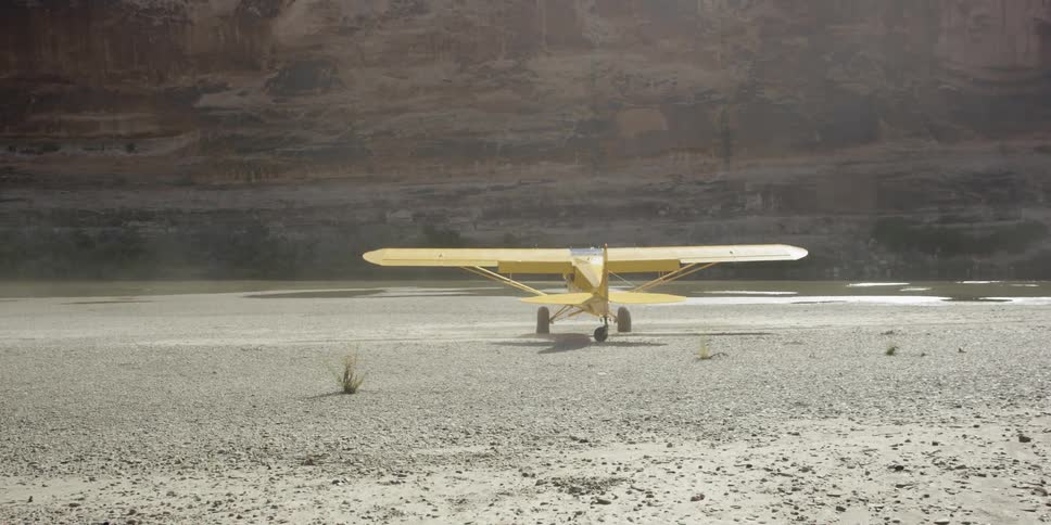 A yellow plane turns on a desert area