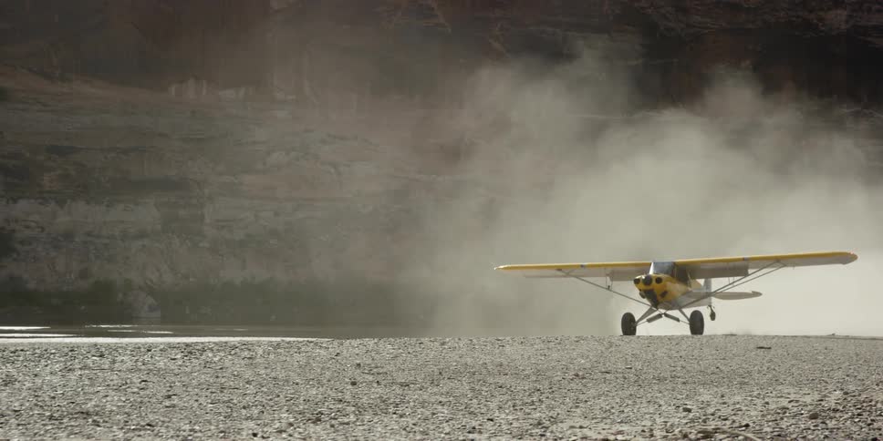 Small yellow plane rolling on a dirt runway