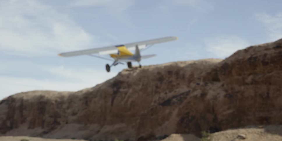 A small plane taking off near cliffs