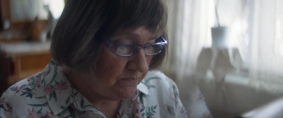 A woman putting on glasses