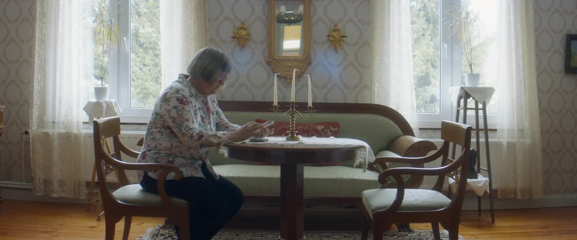 Woman sitting at a table in the living room looking at her smartphone