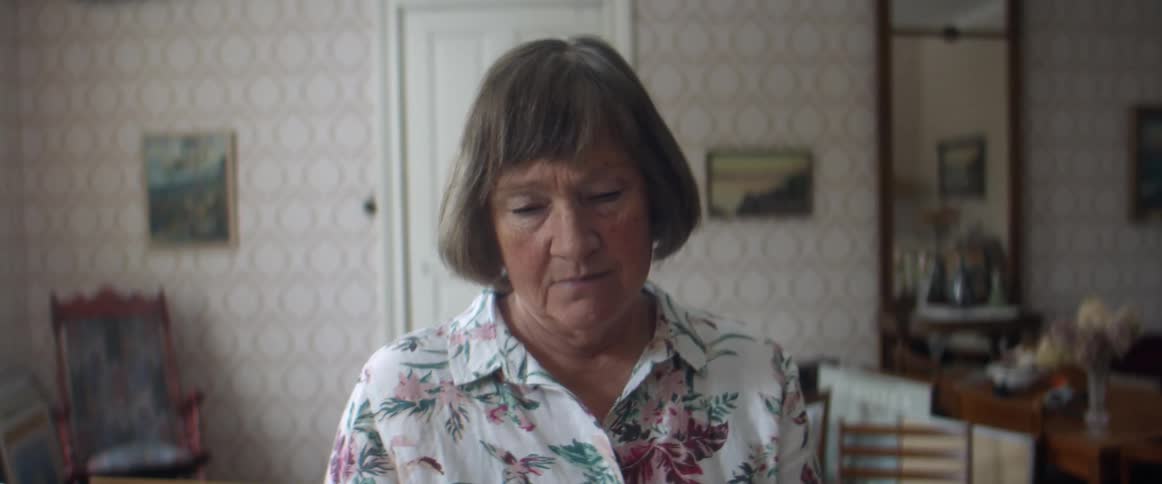 Woman picks up a framed picture in the living room at home