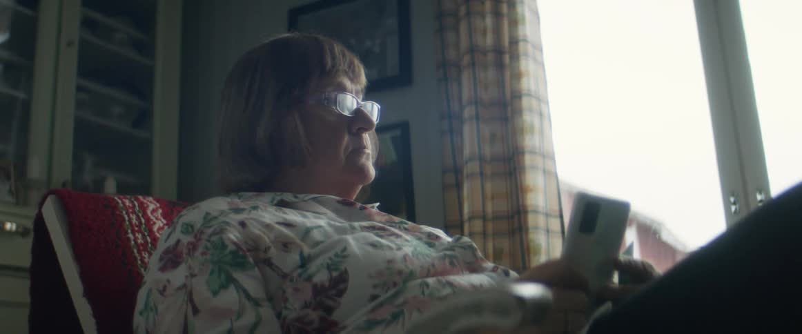 Woman sitting in the living room uses her smartphone impatiently