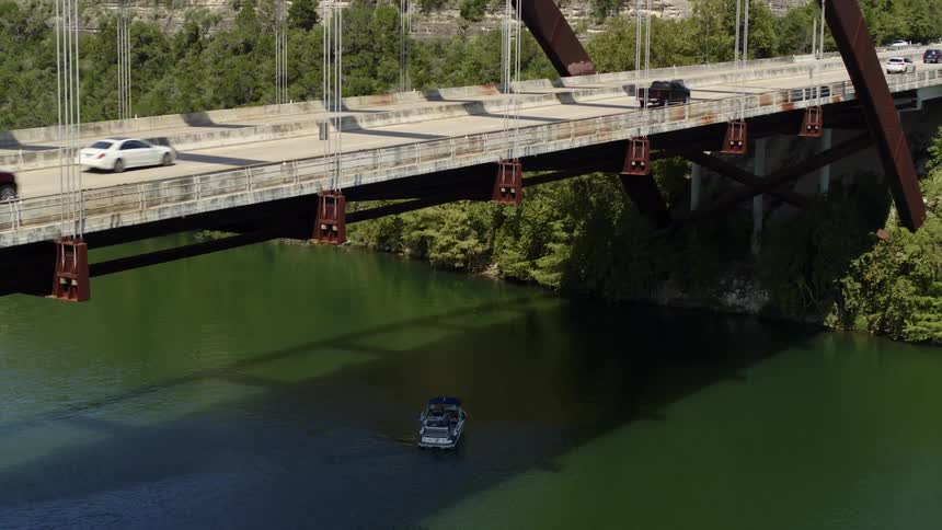 A boat turns around on a river under a traffic bridge