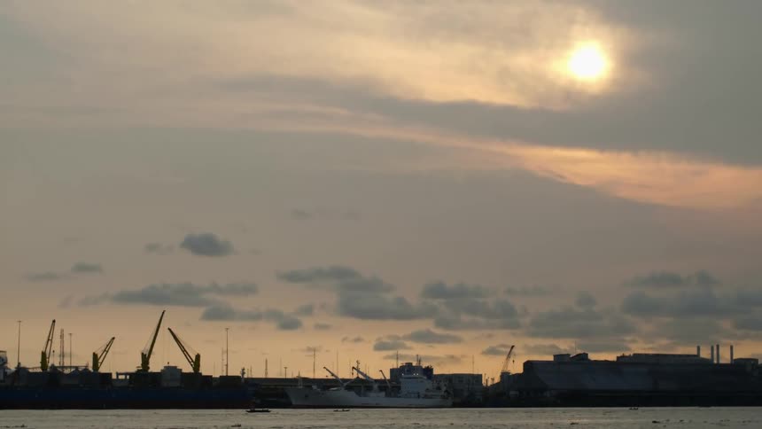 Construction cranes towering on the docks at sunset