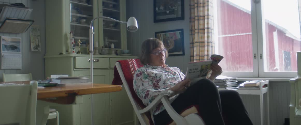 A woman reading a paper in a chair