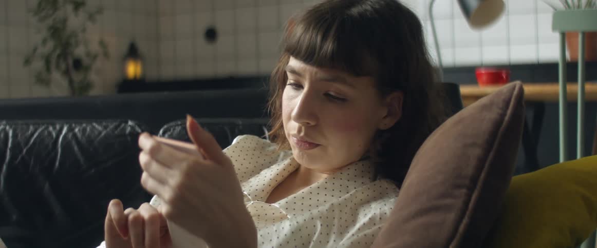 A woman sitting on a couch reading on a smartphone