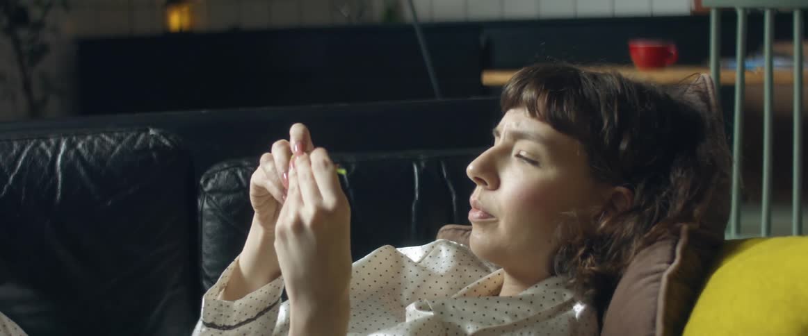 A woman feeling sick and laying on a couch