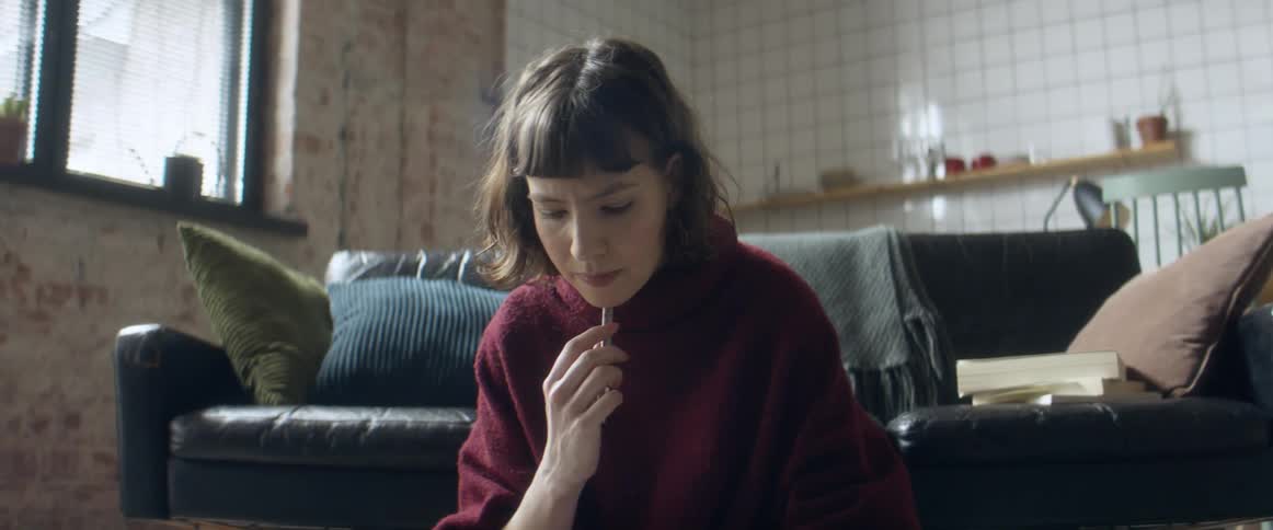 A woman sitting on the floor in front of a couch in a living room during the day having a conversation