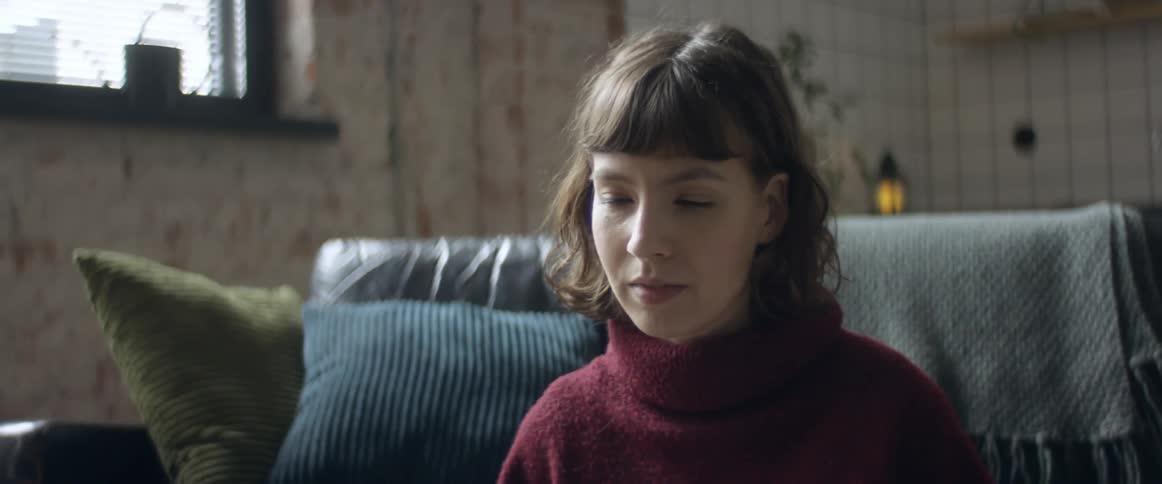 Woman sitting over a rug in the living room talking to a group of friends through a video call