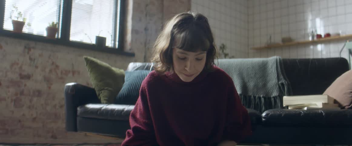 A teenage girl sits on the floor at home and writes