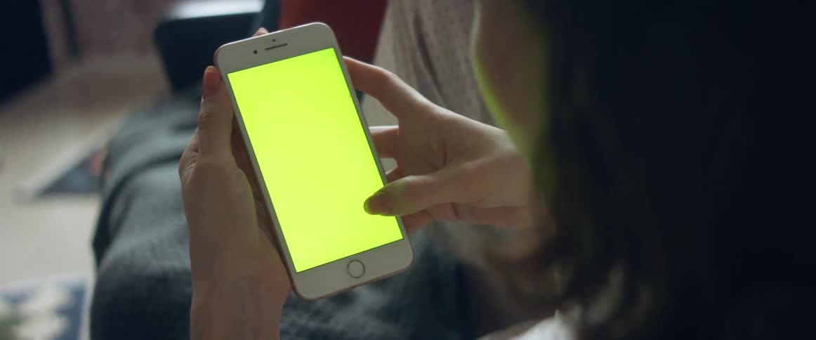 Woman wearing pajamas reclines on sofa scrolling through mobile phone