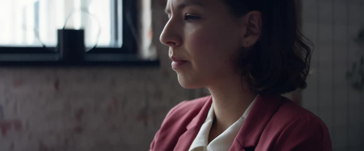 A woman in a room with a pen with a wall and window in the background