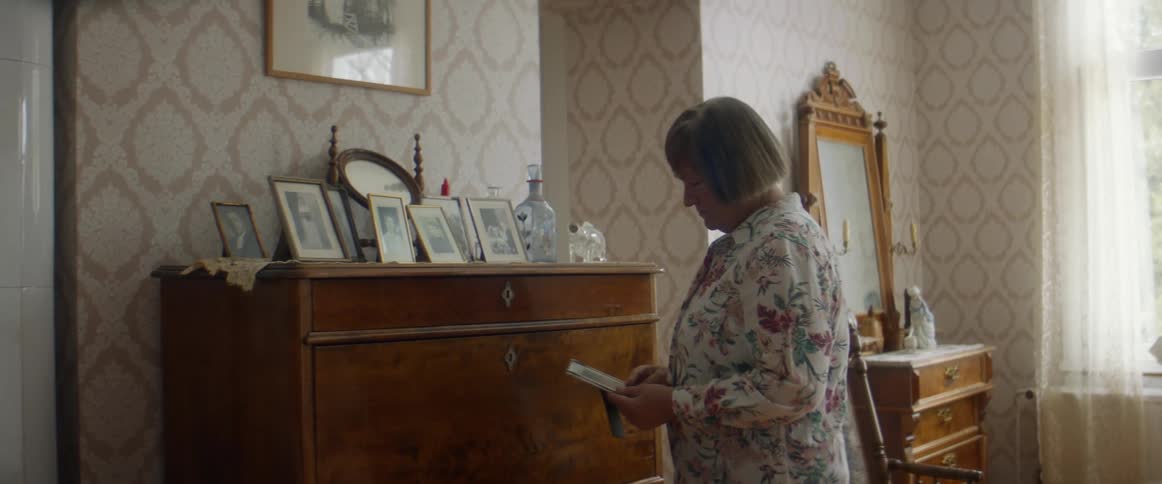 Woman standingin the living room at home looking at framed pictures