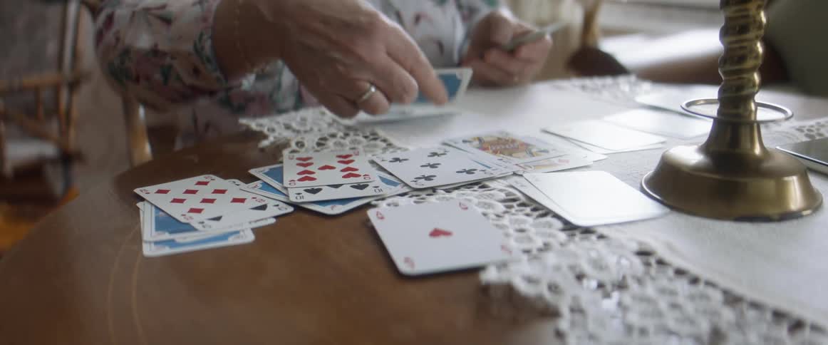 An elderly woman plays cards at home