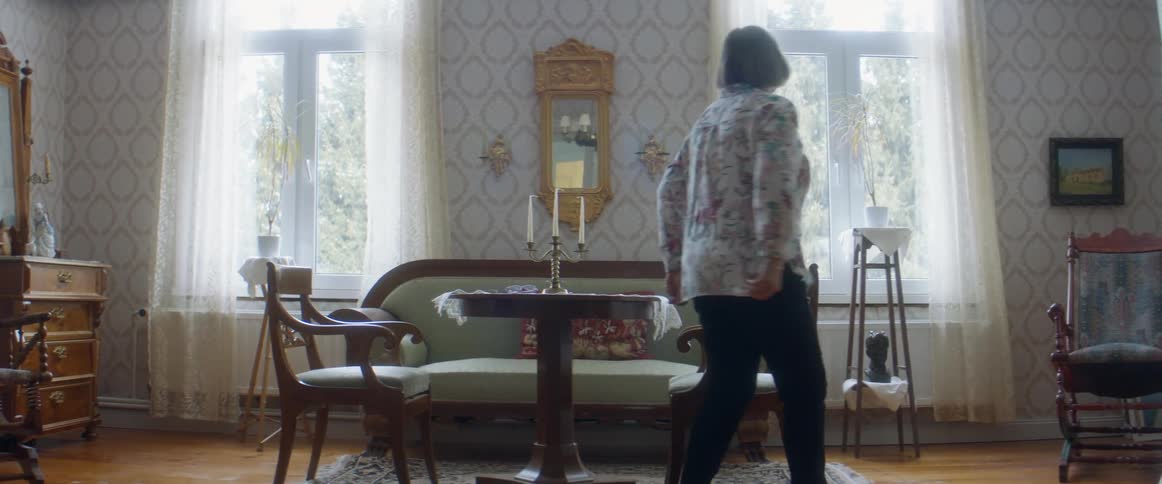 Woman sitting on the living room stands up to look out the window