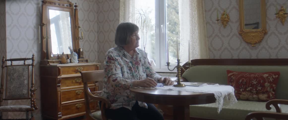 Woman playing solitaire in the living room at home stands up to look out the window