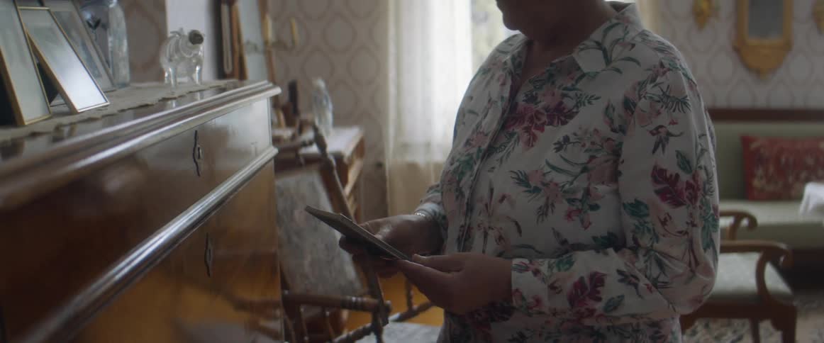 Woman standingin the living room at home looking at framed pictures