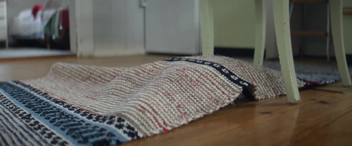 A cat crawling around under a rug