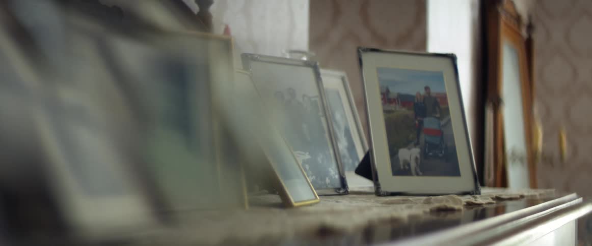 A room with picture frames and a wall in the background