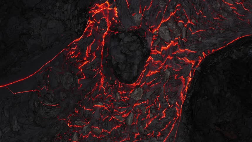A large quantity of molten lava slowly flows down a volcano while releasing smoke into the air