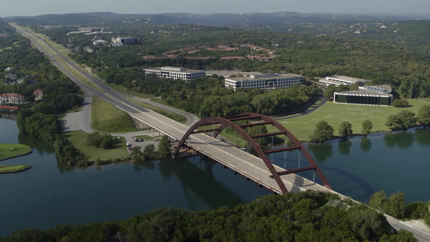 Vehicles driving on an arched bridge over a river in a small town