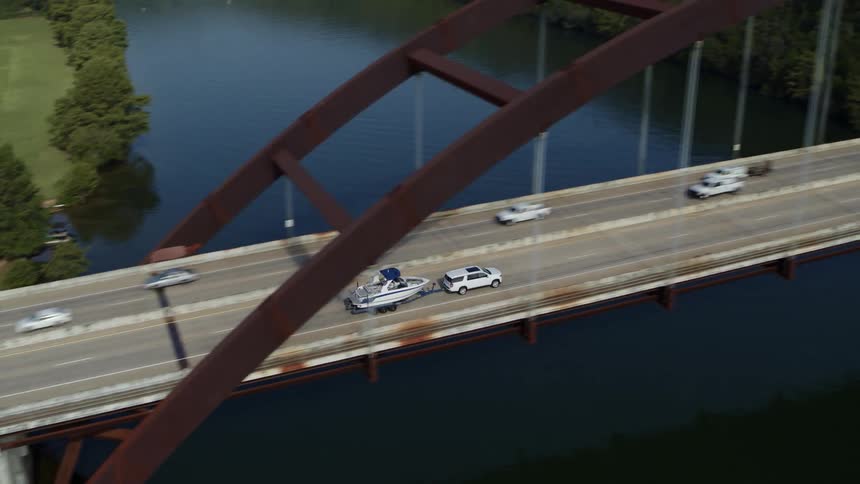 Cars traveling on a bridge over a river near a small town