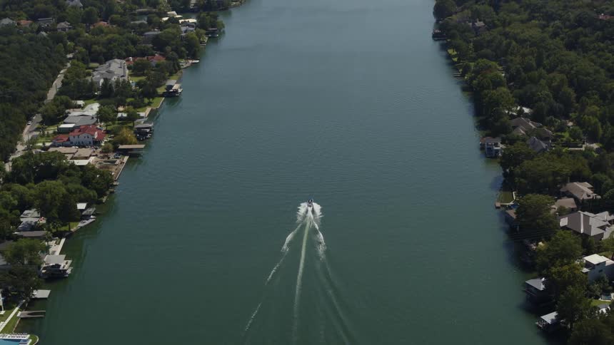Aerial view of a boat driving on a river through a small town in the countryside
