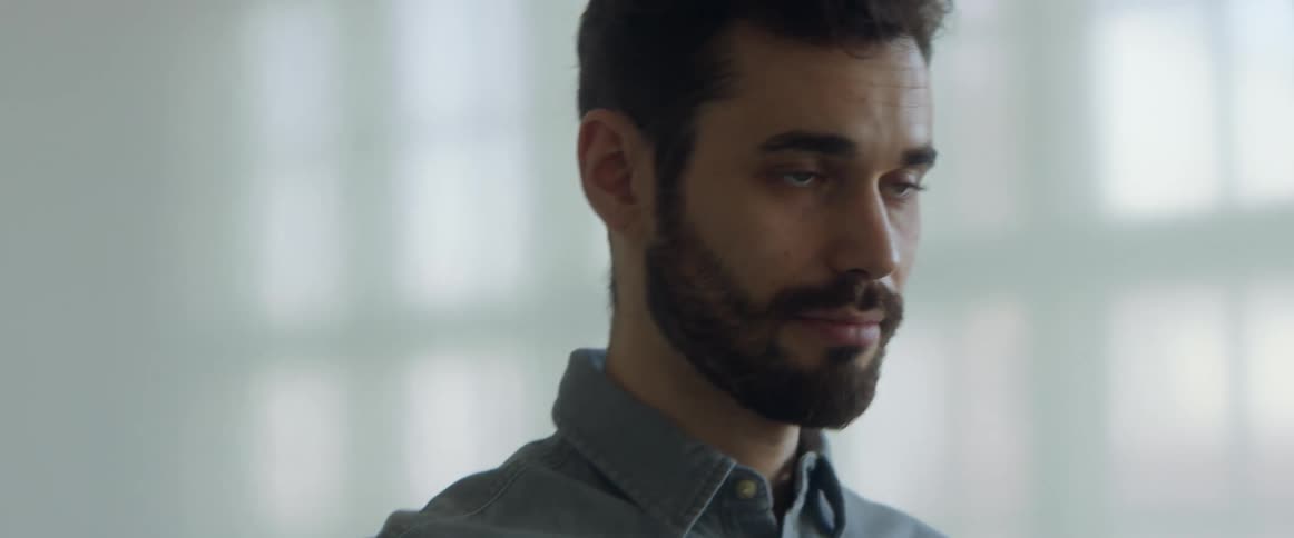 A man with a shirt in a room with a wall and window in the background
