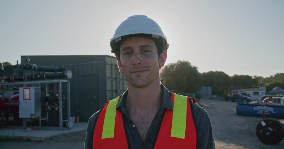 Construction worker wearing hardhat looking at the camera at sunset