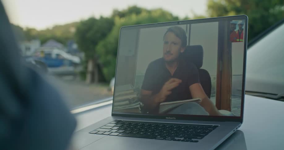 Two employees talk with their boss on a laptop