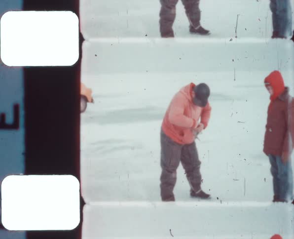 Vintage film footage of a boy standing next to a man in the snow as he digs in his pockets