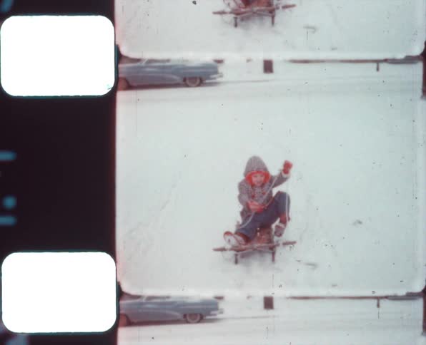 A little boy playing on a sleigh outdoors in the snow on a small slope