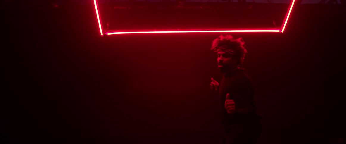 A black male dancing in a dark room that has red neon lighting