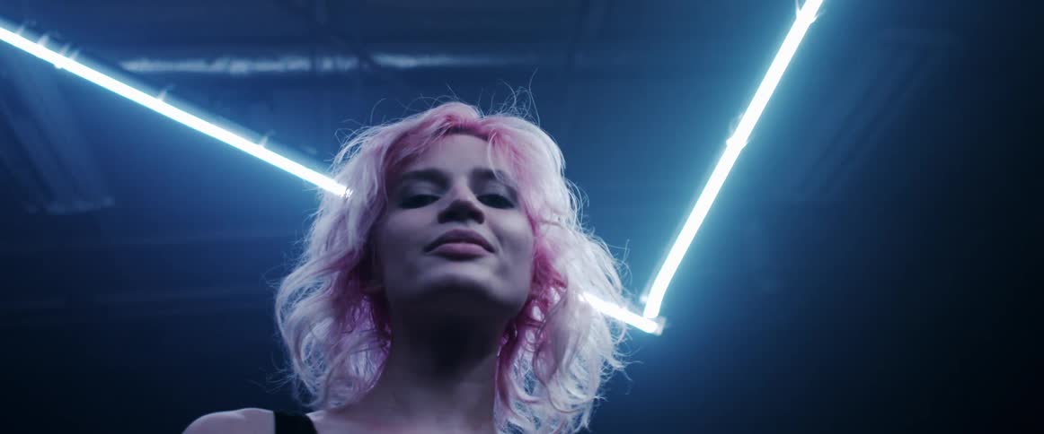 A woman with makeup in a room with lights and the ceiling in the background