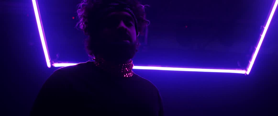 A portrait of a man in a room with purple lighting