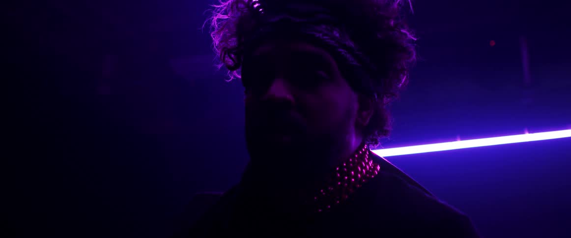 A man with a bandanna and a chain in a room with lights in the background