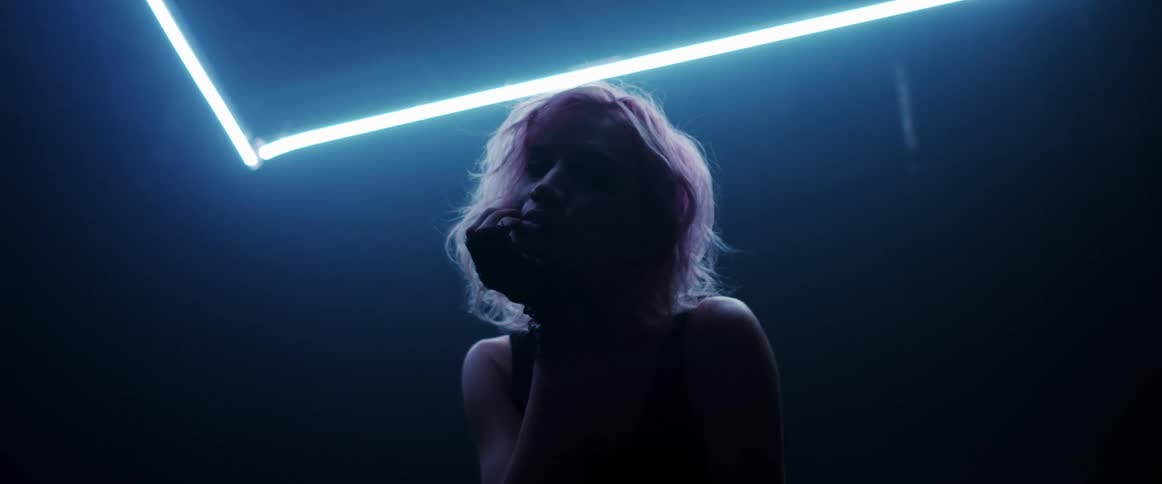 The silhouette of a woman with blond hair is illuminated by neon lights as she poses for the camera