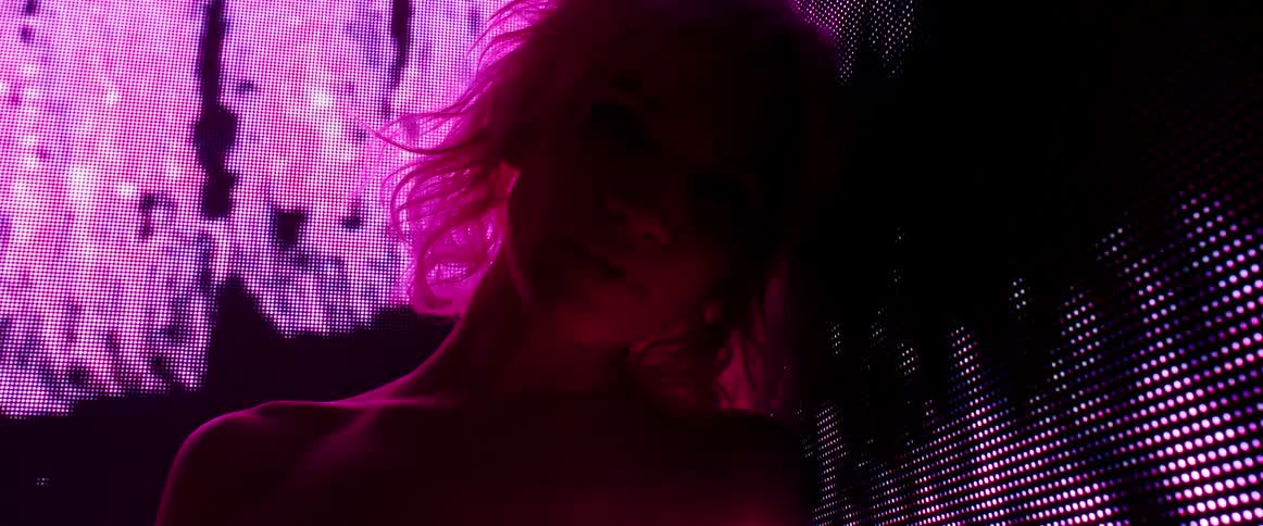 A woman with a dress on a stage with a screen behind her