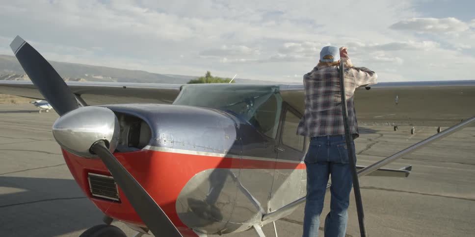 A man is leaning over a plane fueling it