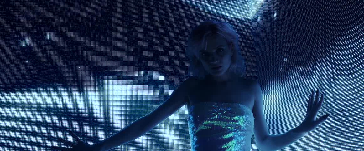 Woman wearing a silver dress standing in front of a digital display