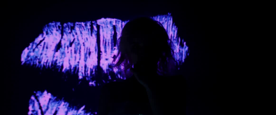 A woman walks in front of bright flashing lights