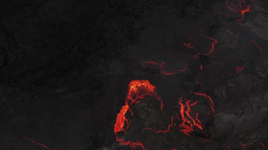 Aerial view of hot red lava erupting from a volcano at night