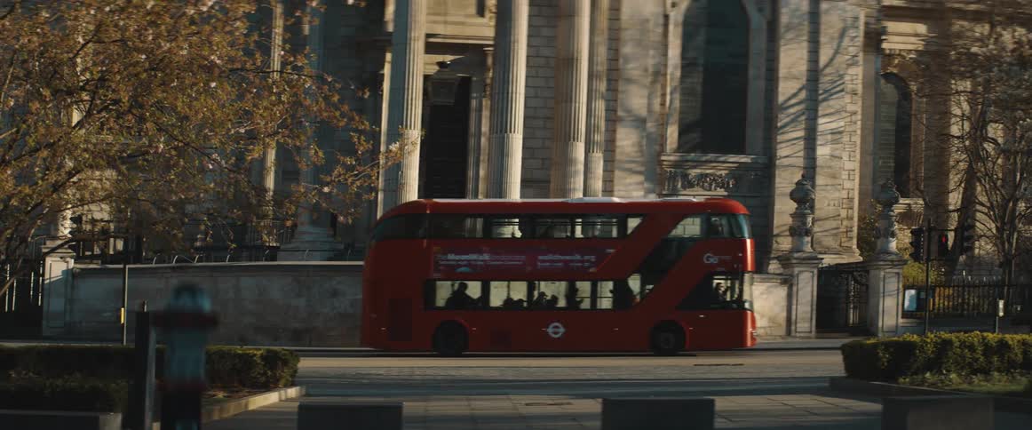 Double decker red bus driving on a city street at evening