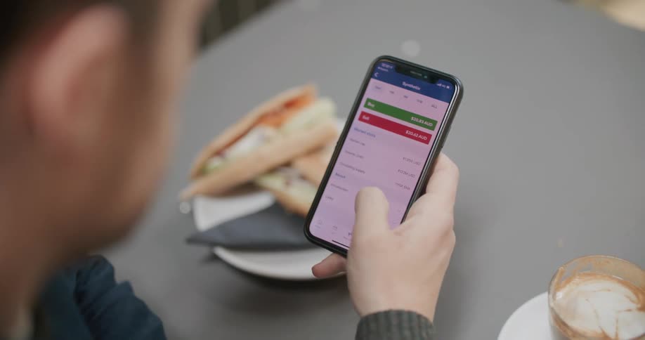 Man sitting at a table uses a smartphone in the cafeteria