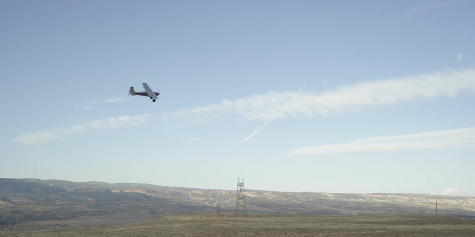 A plane is flying over a green field